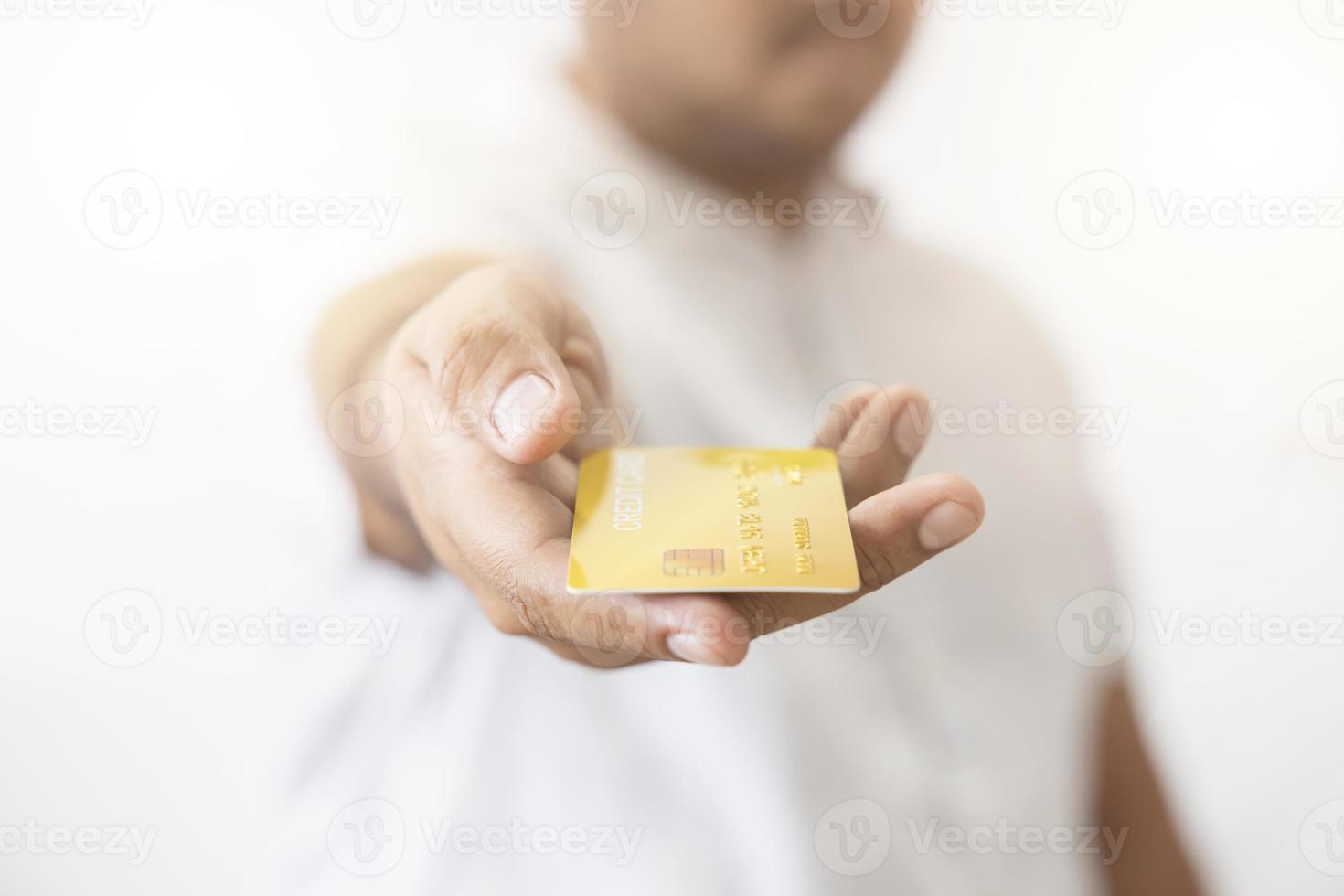 main en gros plan d'un homme asiatique tenant une carte de crédit en or jaune dans sa main. isolé sur fond blanc. concept de finance, commerce, communication, social, technologie, entreprise photo