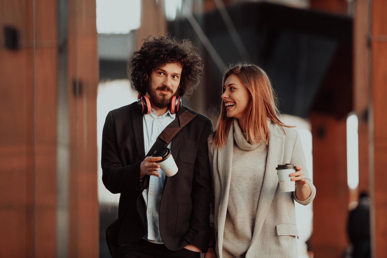 deux personnes en pause de travail marchent devant une entreprise moderne où elles travaillent et boivent du café. photo