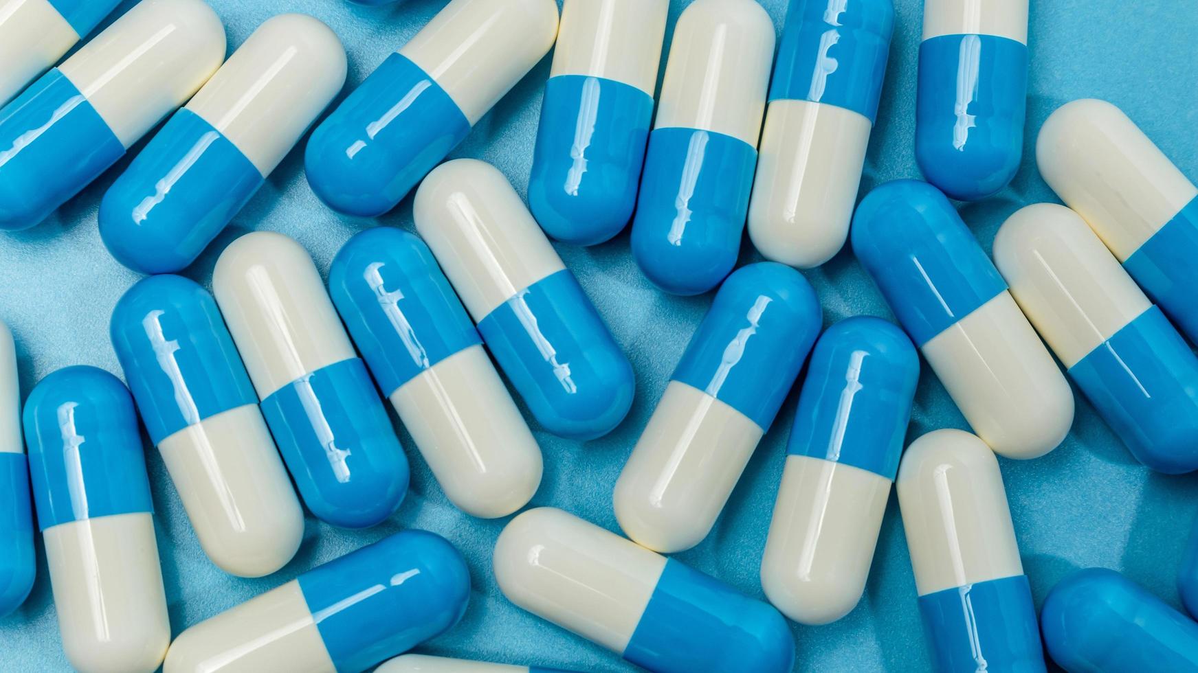 médicament, capsule bleue et blanche sur fond bleu photo