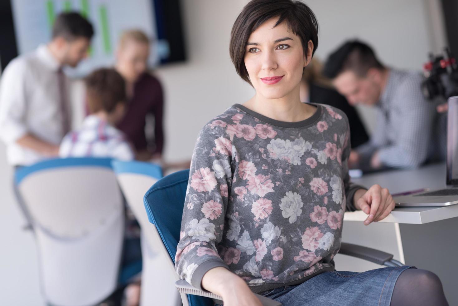 portrait d'une jeune femme d'affaires au bureau avec une équipe lors d'une réunion en arrière-plan photo