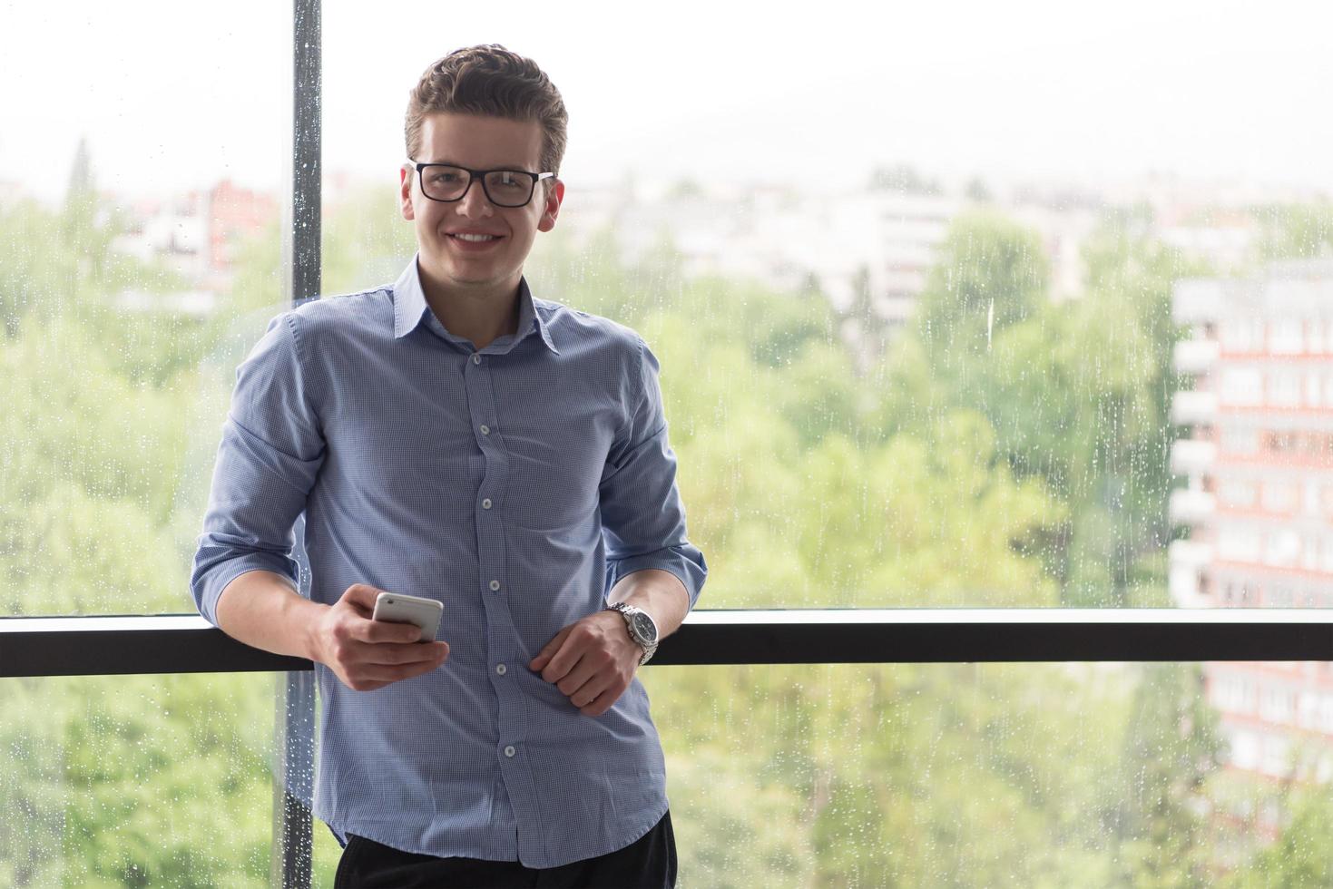 homme d'affaires debout dans un bâtiment moderne près de la fenêtre avec téléphone photo