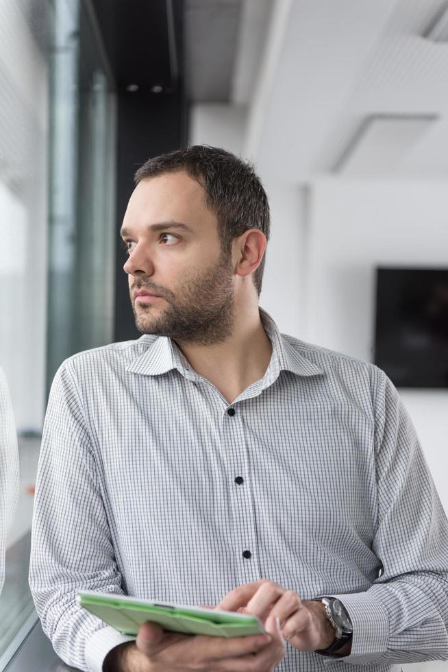 homme d'affaires utilisant une tablette dans un immeuble de bureaux par fenêtre photo