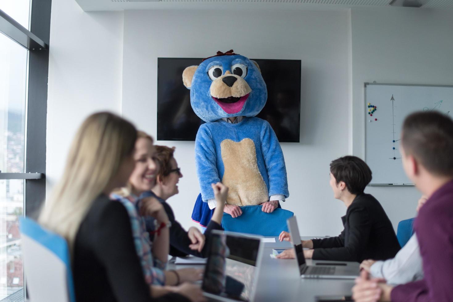 patron habillé en ours s'amusant avec des gens d'affaires dans un bureau branché photo