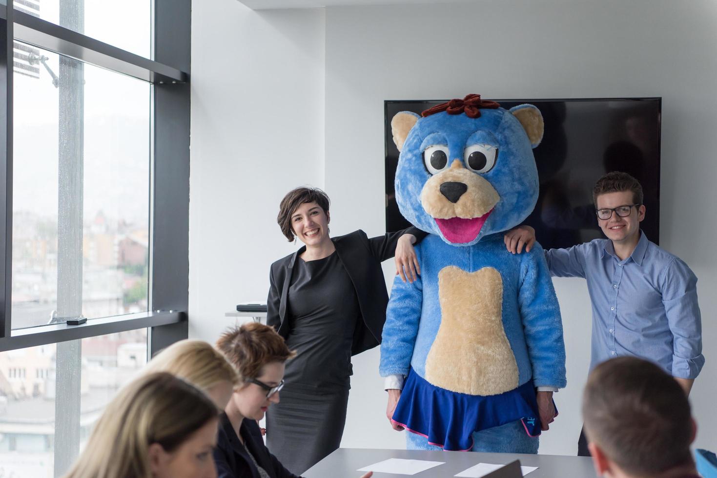 patron habillé en ours s'amusant avec des gens d'affaires dans un bureau branché photo