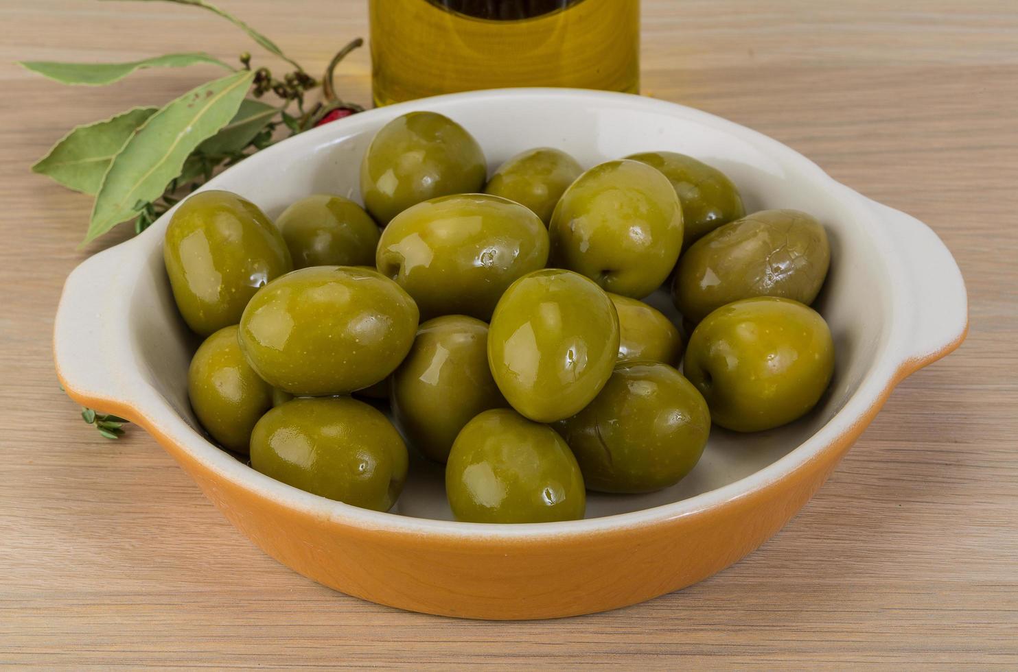 olives vertes dans un bol sur fond de bois photo