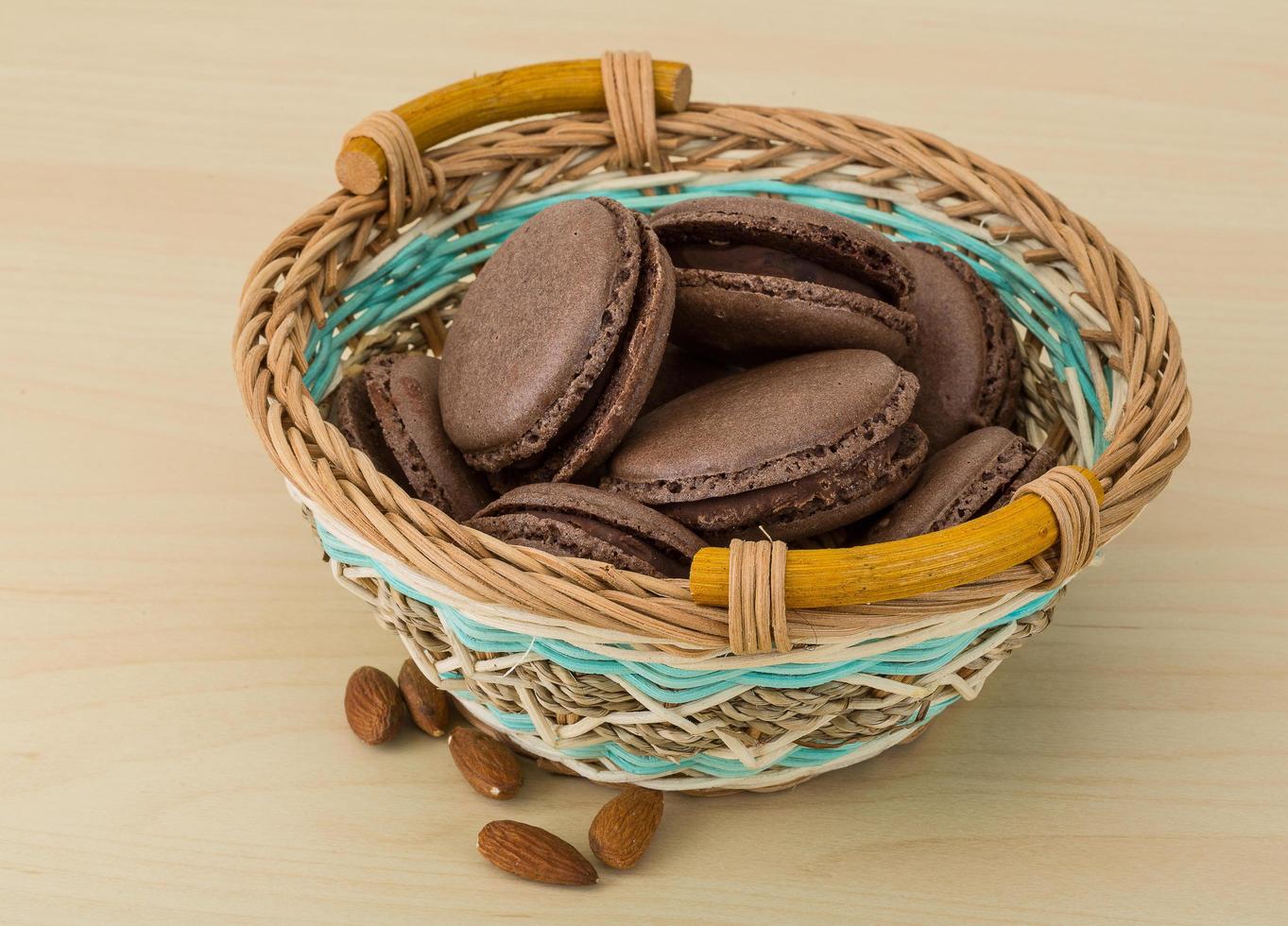 macarons au chocolat dans un panier sur fond de bois photo