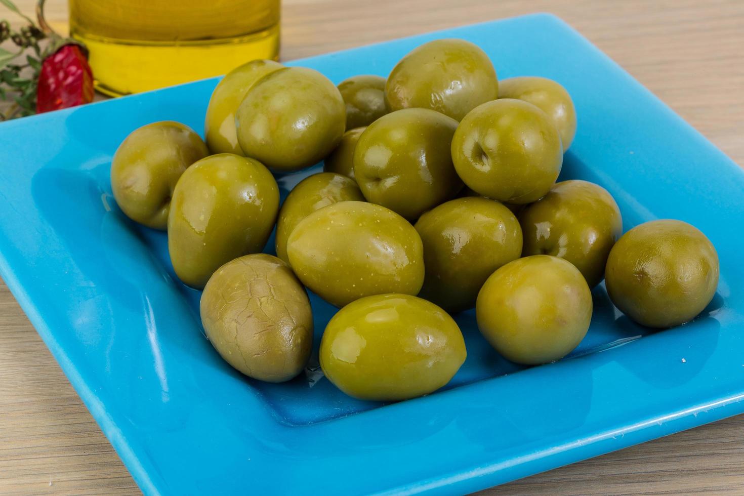 olives vertes sur la plaque et fond en bois photo