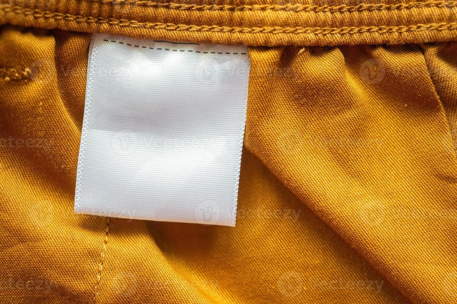 Étiquette d'étiquette de vêtements vierge blanche sur fond de texture de tissu de short en coton marron photo