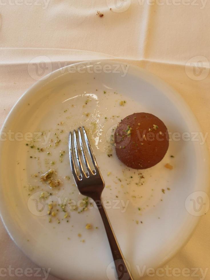 l'un des desserts en dinde, le gulab jamun, qui est servi jusqu'à deux morceaux sur une assiette blanche. photo