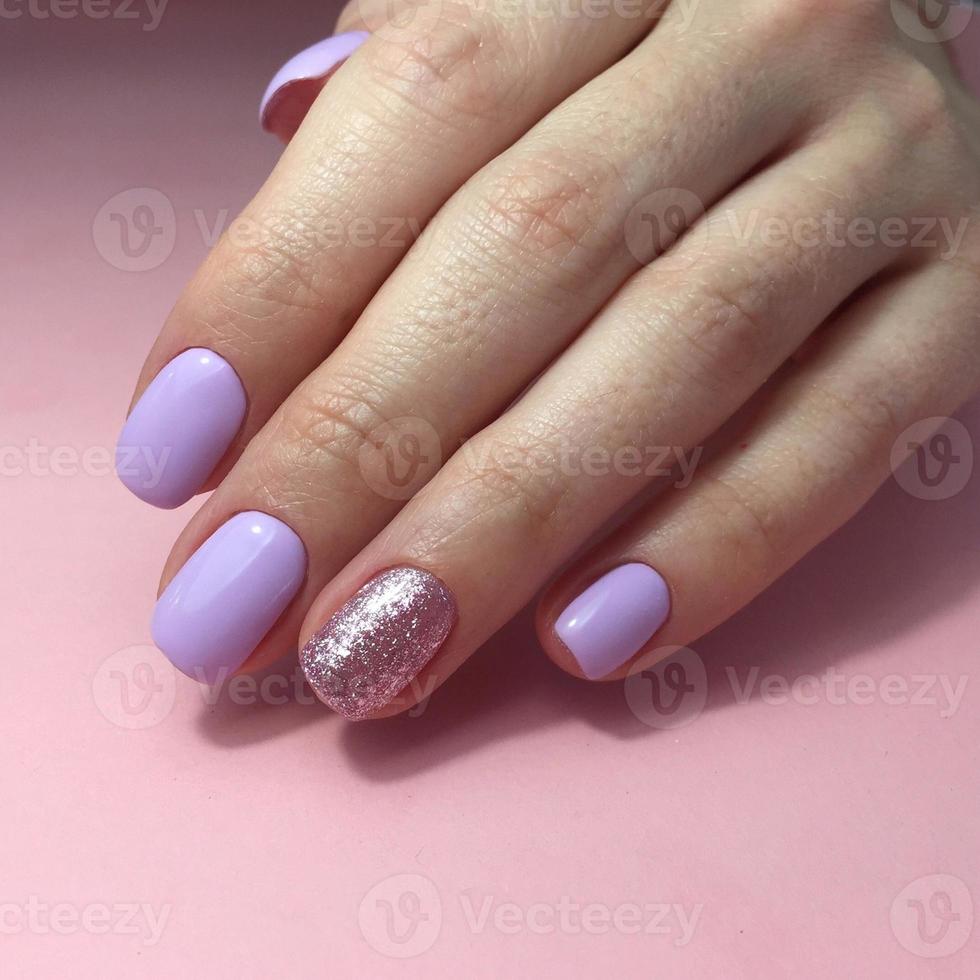 manucure de différentes couleurs sur les ongles. manucure féminine sur la main sur fond rose photo