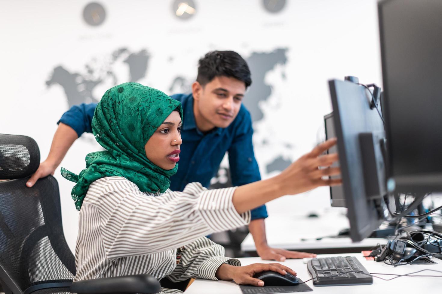 équipe d'affaires de démarrage multiethnique femme arabe portant un hijab lors d'une réunion dans un brainstorming intérieur de bureau ouvert moderne, travaillant sur un ordinateur portable et un ordinateur de bureau. mise au point sélective photo