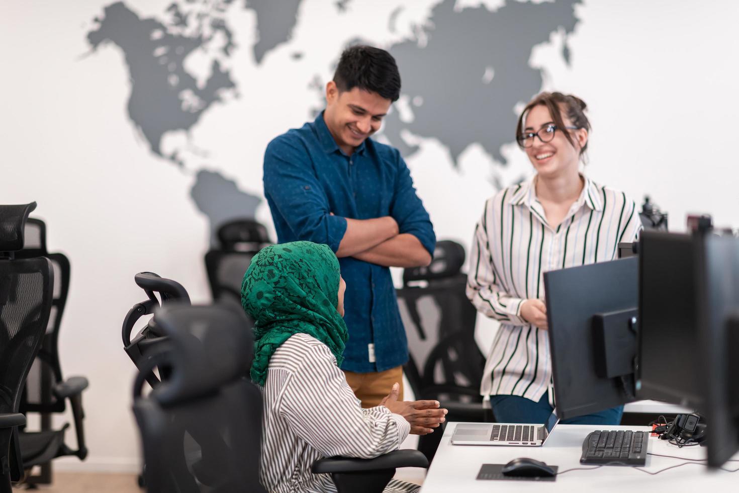 équipe d'affaires de démarrage multiethnique femme arabe portant un hijab lors d'une réunion dans un brainstorming intérieur de bureau ouvert moderne, travaillant sur un ordinateur portable et un ordinateur de bureau. mise au point sélective photo