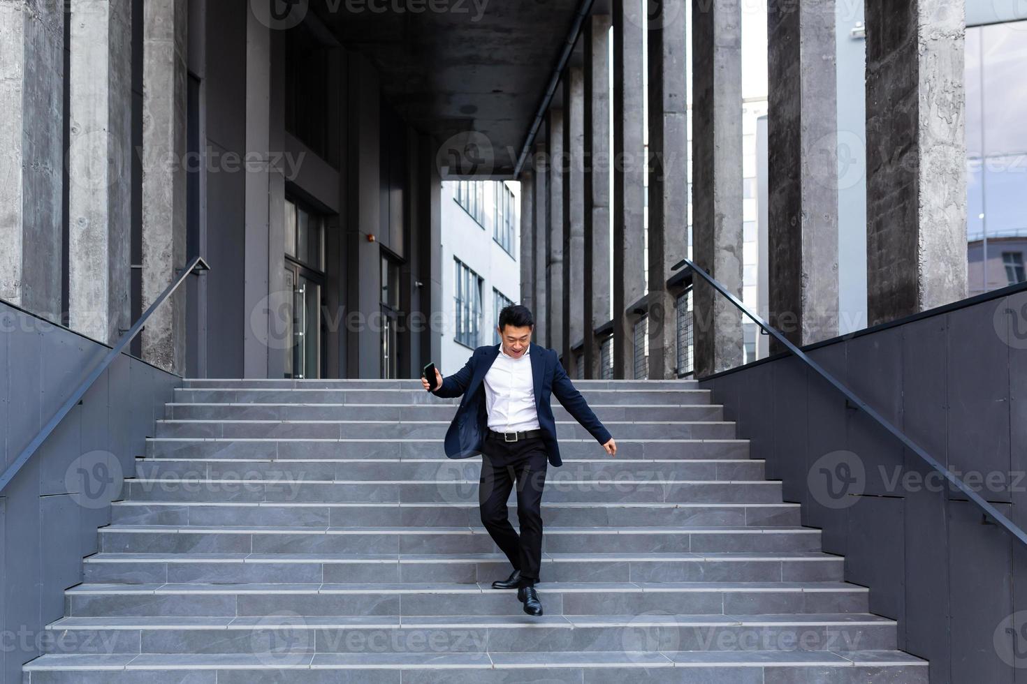 un homme d'affaires asiatique heureux et joyeux dansant près du bureau se réjouit de la victoire et du succès photo