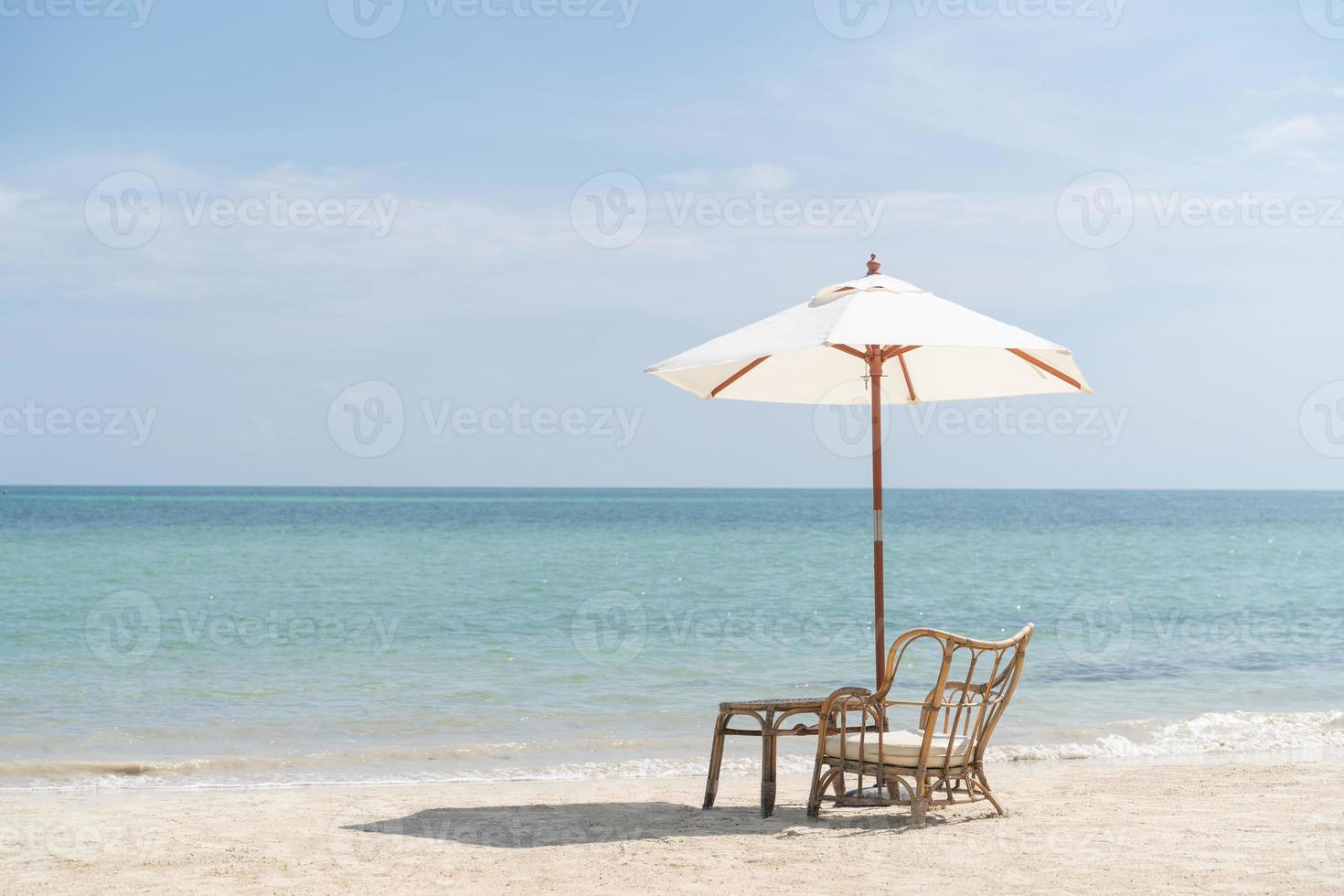 une table avec des chaises et un parasol mis en place pour un repas romantique sur la plage, ciel et mer en arrière-plan. photo