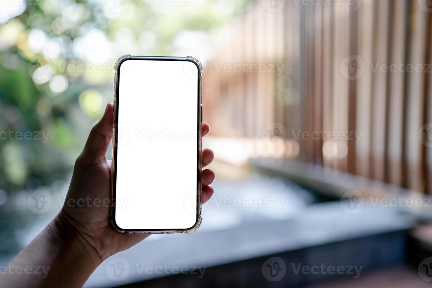 mains tenant un téléphone portable blanc avec maquette d'écran vierge, arrière-plan spa de l'hôtel. photo