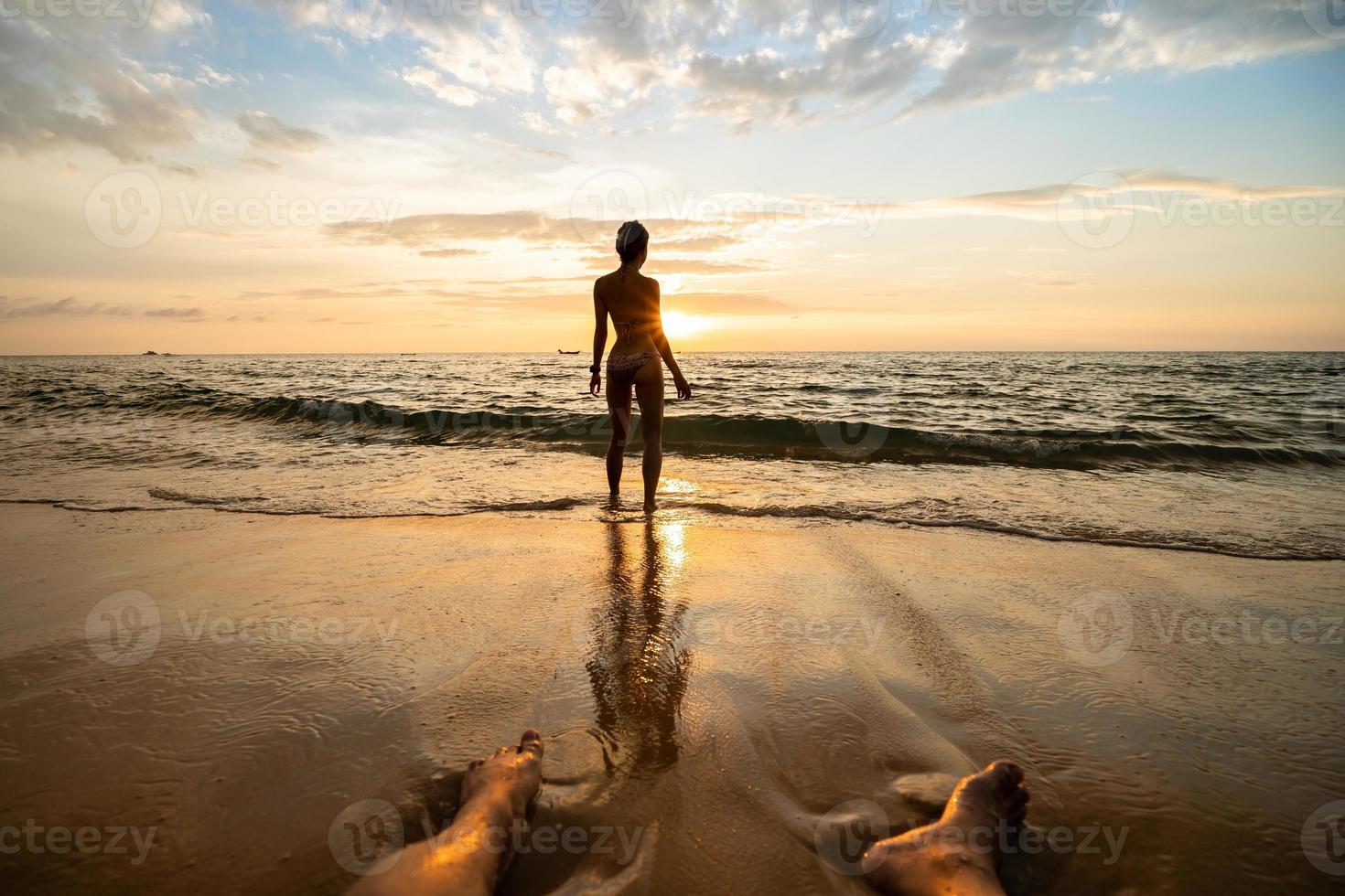 silhouette de femme sur la plage au coucher du soleil avec des jambes d'homme. photo