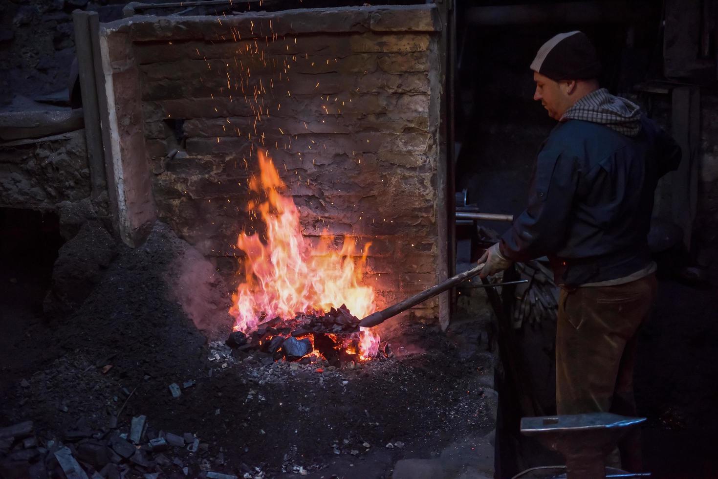 jeune forgeron traditionnel travaillant avec feu ouvert photo