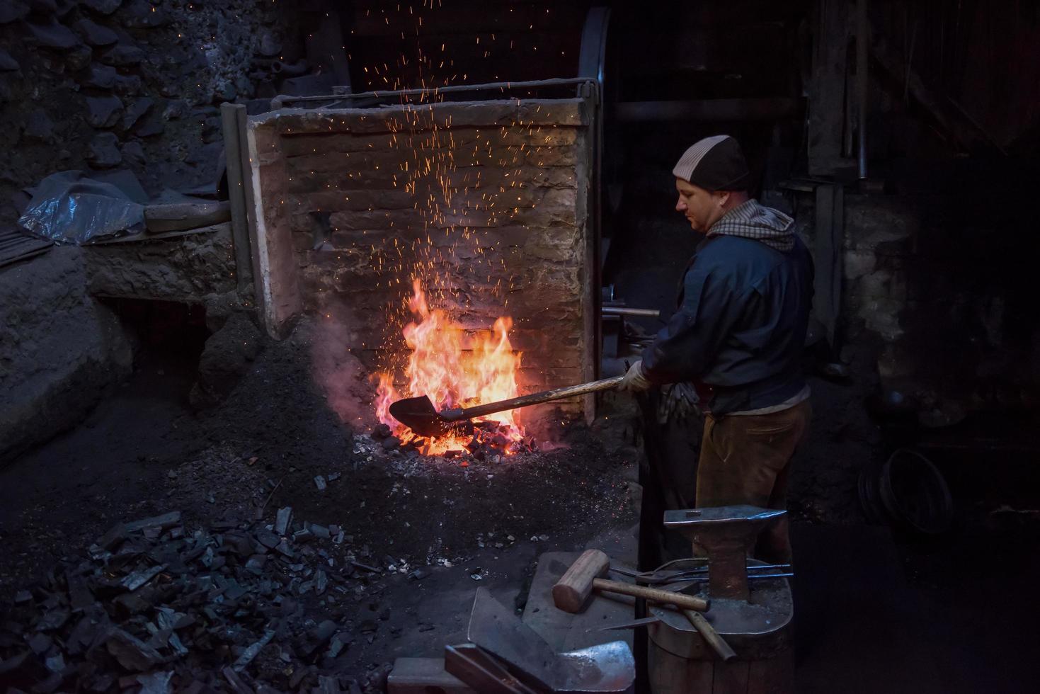 jeune forgeron traditionnel travaillant avec feu ouvert photo