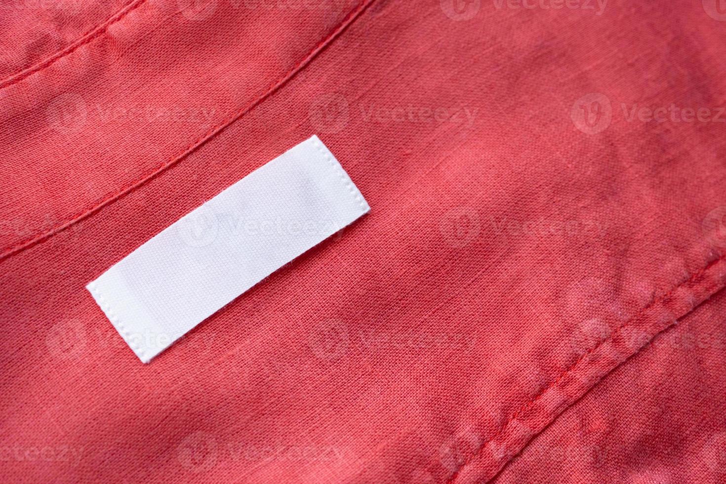 Étiquette d'étiquette de vêtements blanc vierge sur fond de texture de tissu de chemise en lin rouge photo