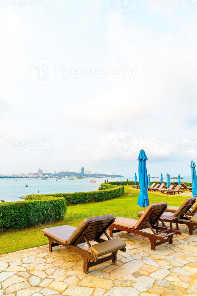 chaise piscine ou lit piscine et parasol autour de la piscine avec fond de plage de mer photo