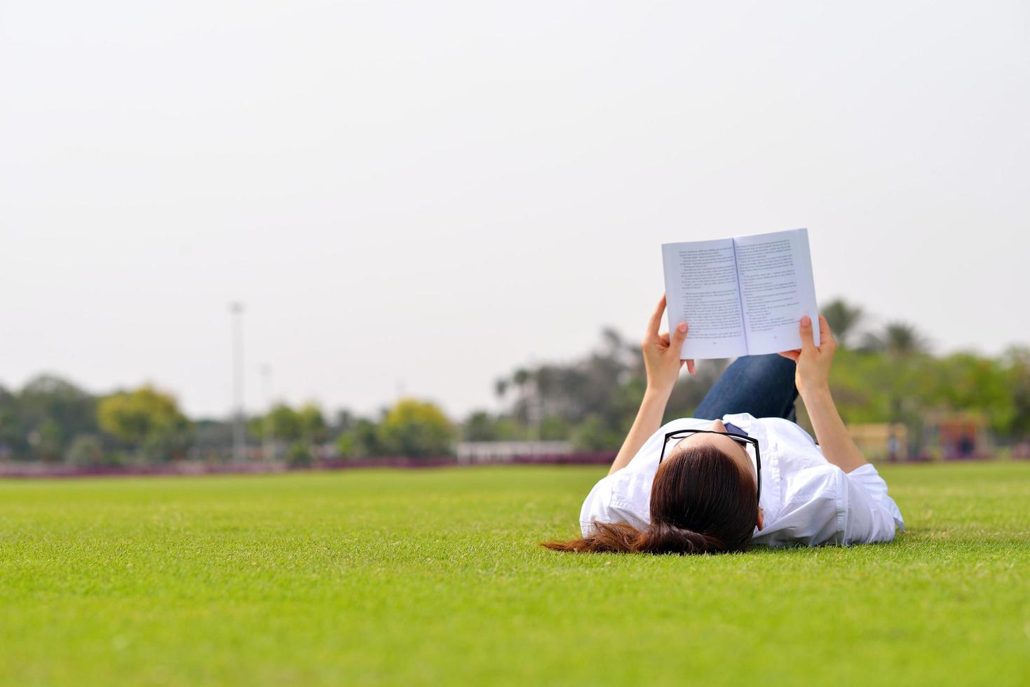 jeune femme lisant un livre dans le parc photo