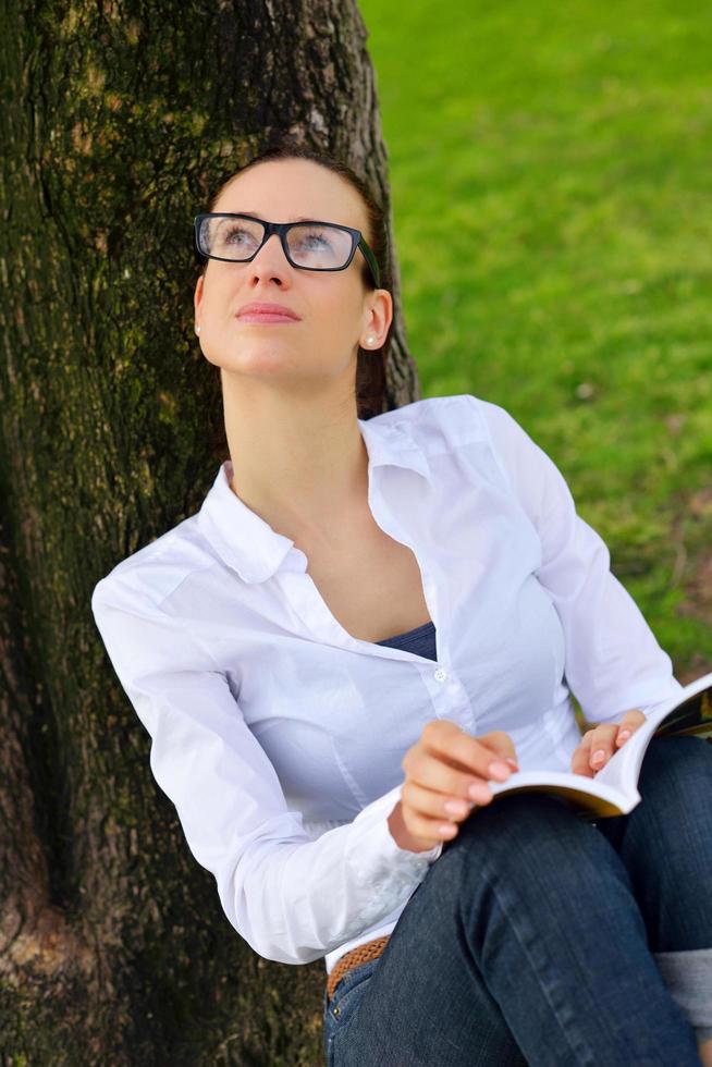 jeune femme lisant un livre dans le parc photo