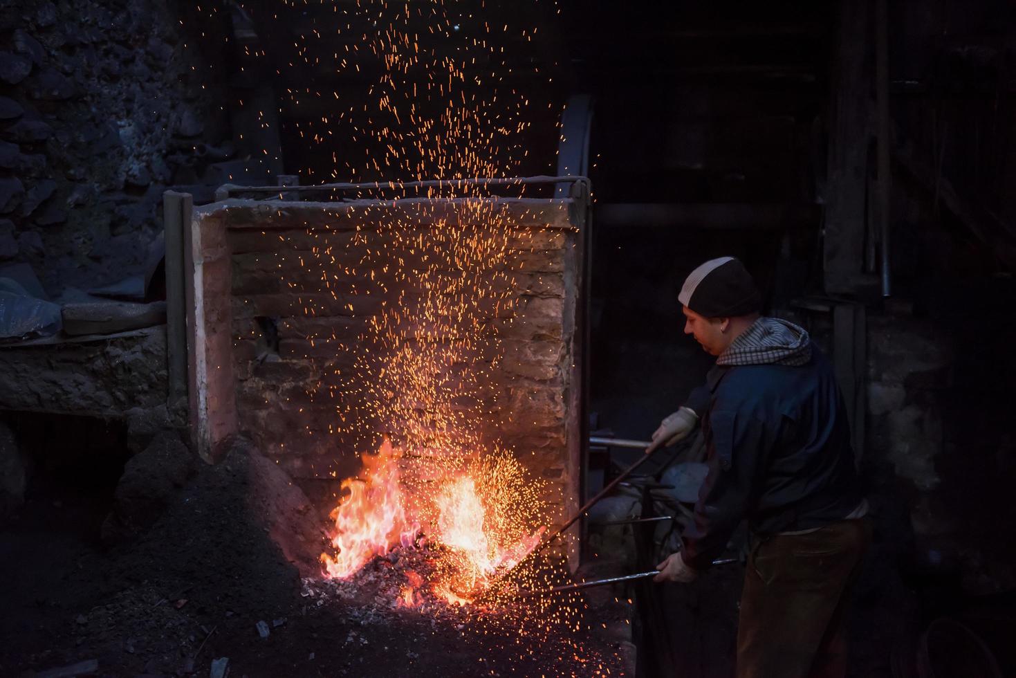 jeune forgeron traditionnel travaillant avec feu ouvert photo