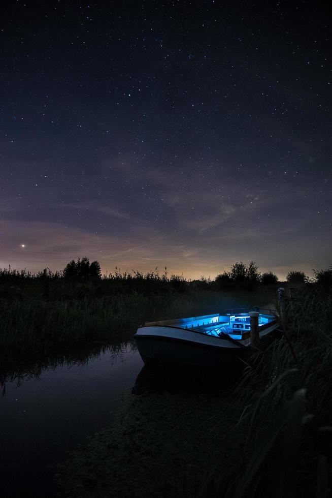 bateau bleu et blanc illuminé sur la rivière photo