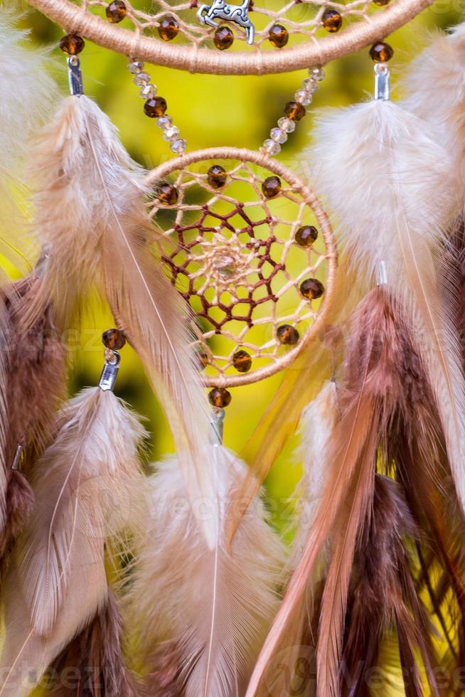 attrape-rêves fait à la main avec des fils de plumes et des cordes de perles suspendues photo