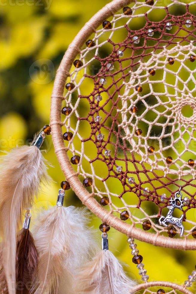 attrape-rêves fait à la main avec des fils de plumes et des cordes de perles suspendues photo