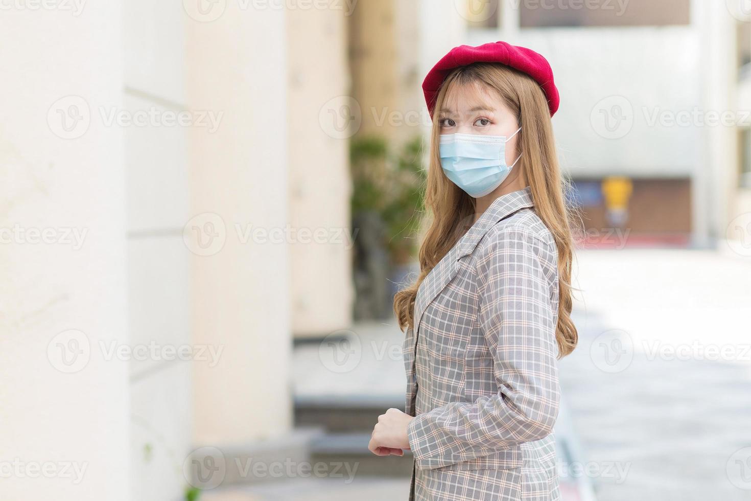 belle femme asiatique aux longs cheveux bronze qui porte un costume gris et se promène dans la ville et portant un masque médical dans les soins de santé, la pollution, le nouveau concept de mode de vie normal et de protection contre les coronavirus. photo