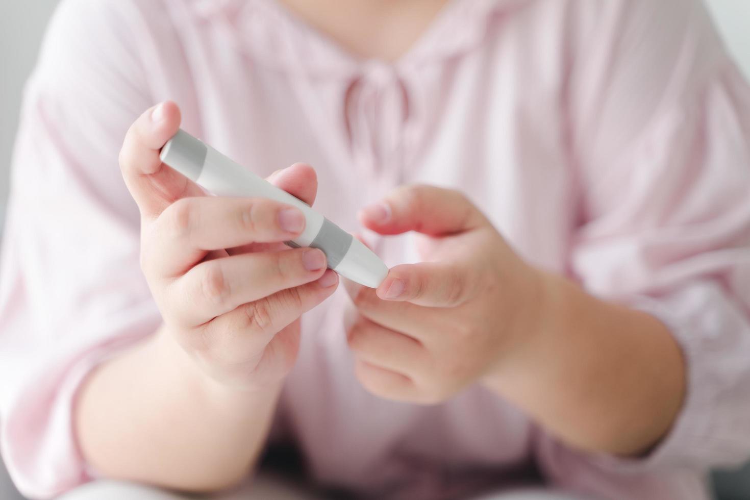 femme asiatique utilisant une lancette sur le doigt pour vérifier la glycémie par glucomètre, soins de santé et médecine, diabète, concept de glycémie photo