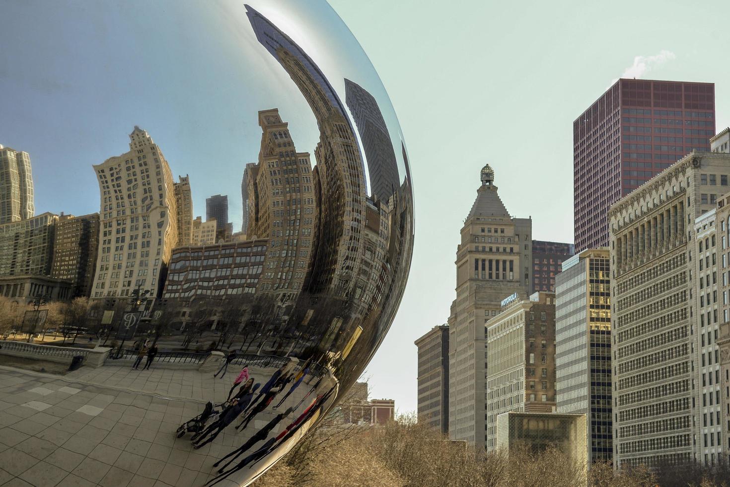 chicago, il, états-unis - 22 mars 2018 - reflétant les bâtiments sur la statue de la porte des nuages dans le millenium park, ville centrale, avec quelques touristes se promenant photo