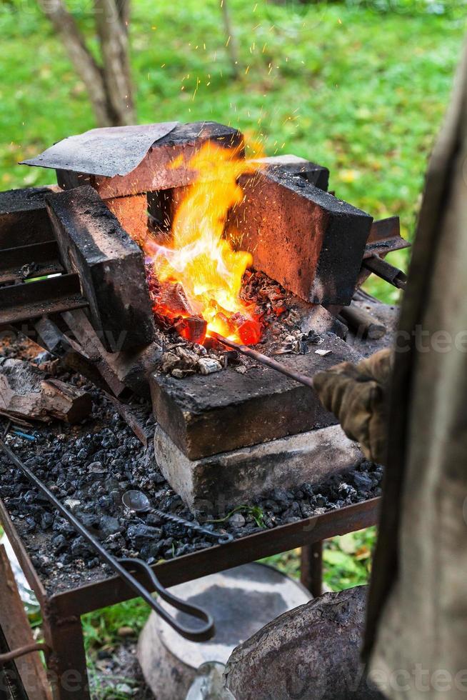 Le forgeron chauffe la tige d'acier dans le four de forgeage photo