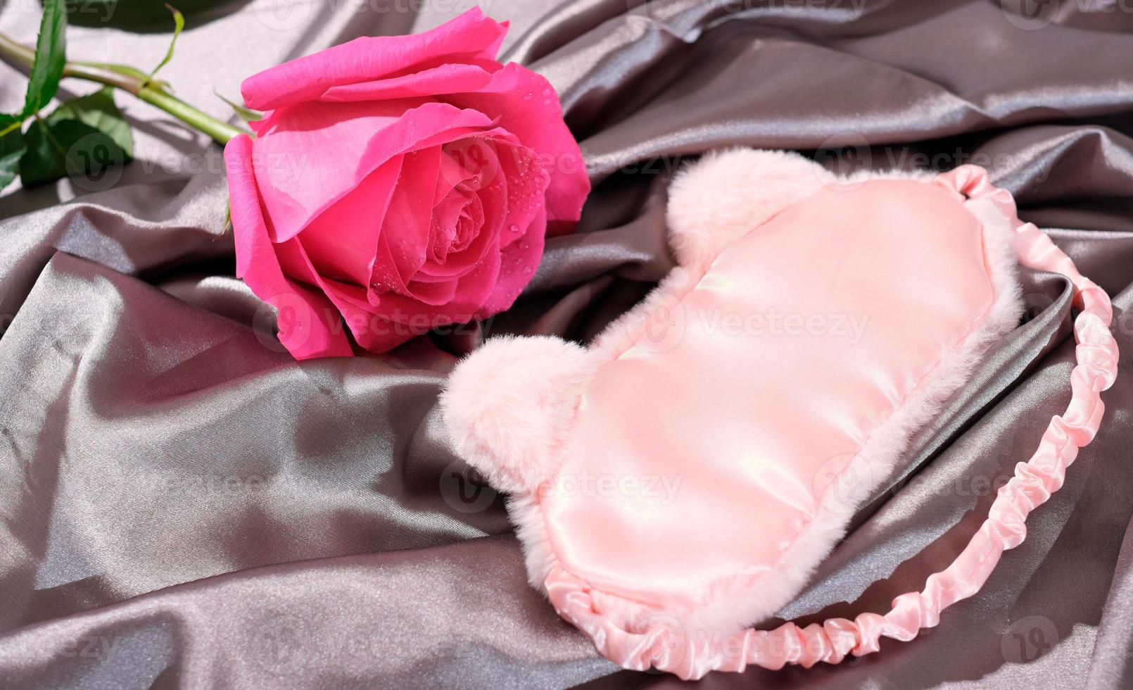 masque de sommeil sur un drap de soie et rose rose, concept de soirée romantique, rencontres et amour, relation. photo