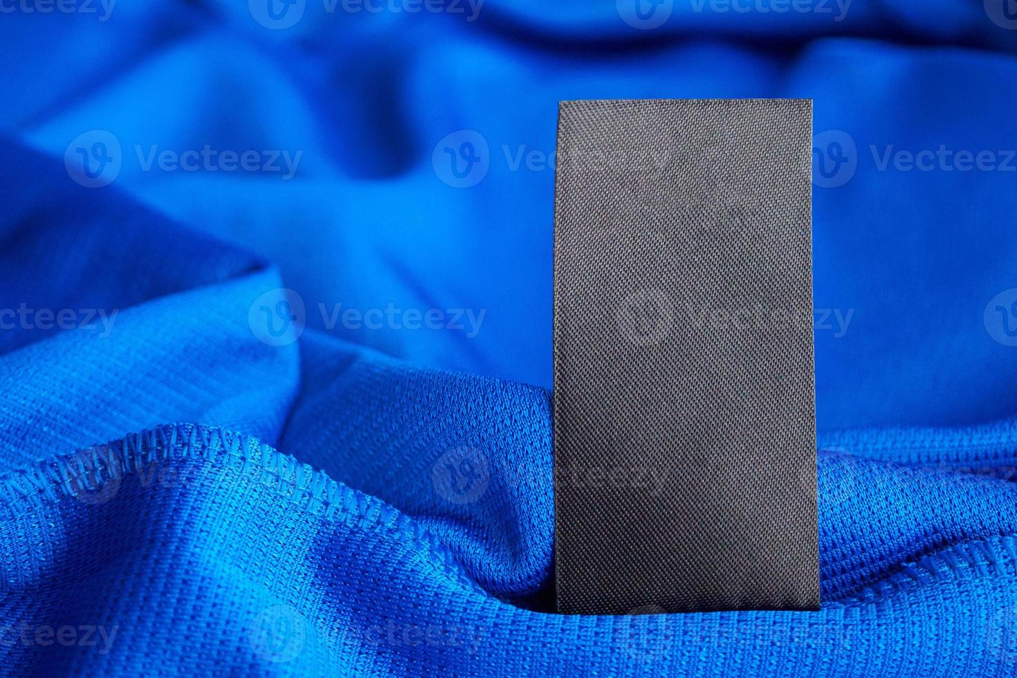 Étiquette de vêtements de soin de lessive vierge noire sur fond de chemise de sport en polyester jersey bleu photo