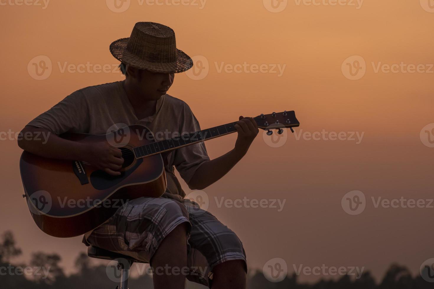 gros plan, de, homme, dans, chapeau, jouer guitare, à, coucher soleil photo