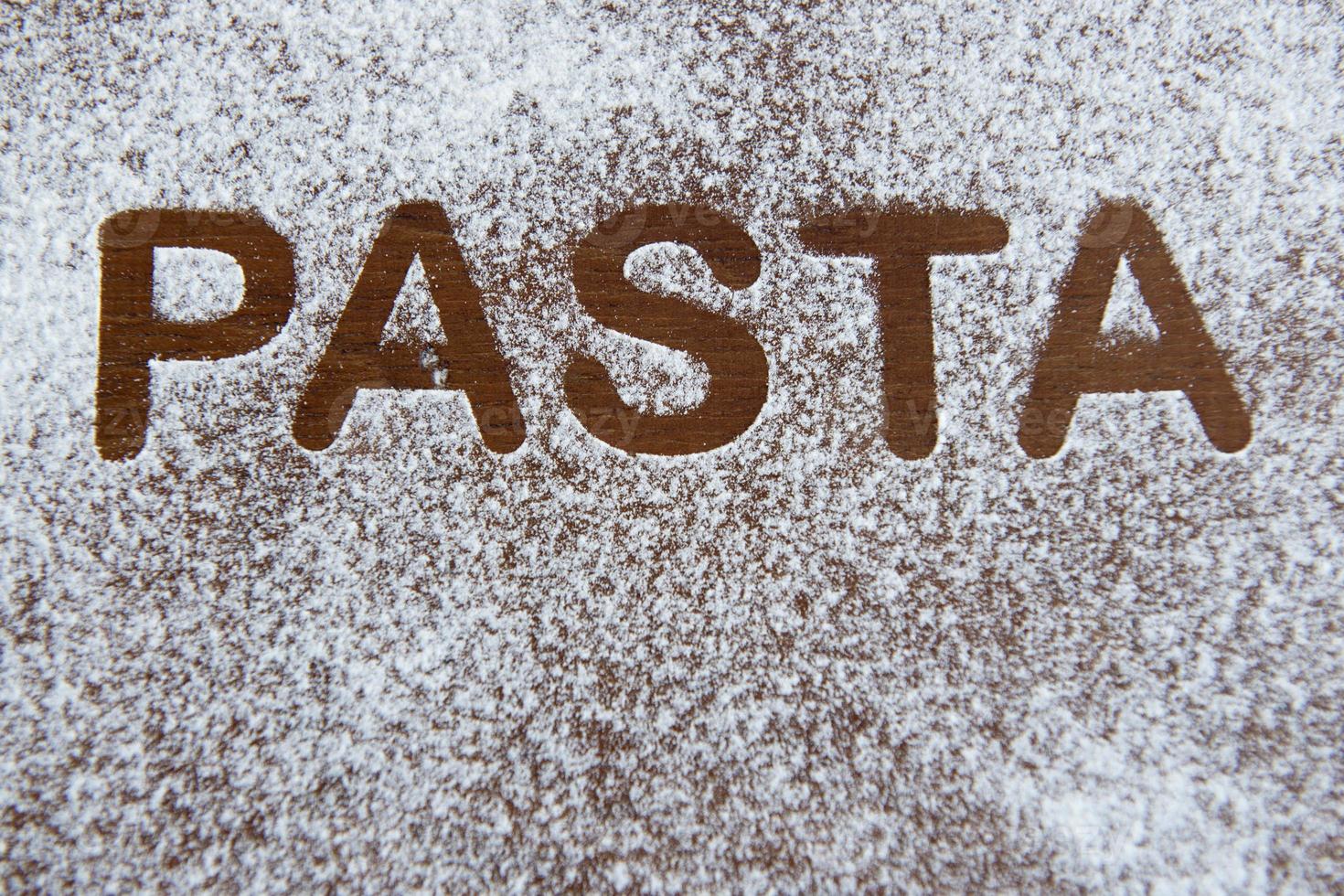 Fond en bois avec de la farine saupoudrée et le mot pâtes écrit photo