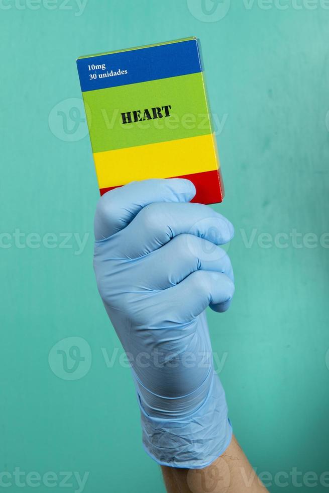 médecin tenant une boîte de médecine cardiaque écrite sur une boîte avec des gants de protection photo