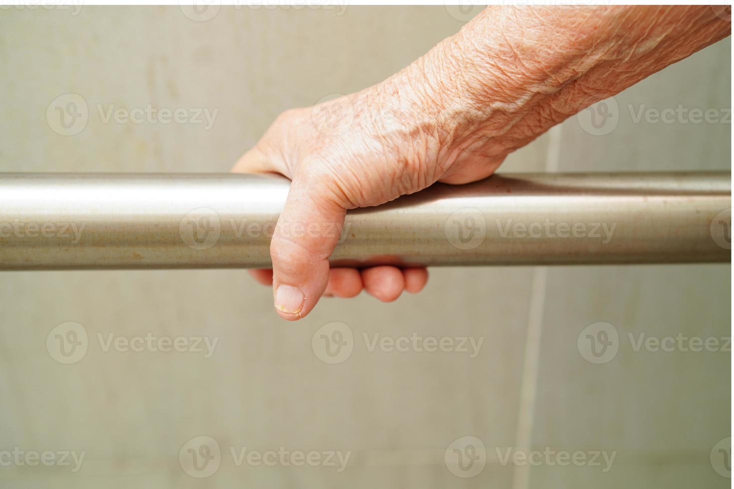 une vieille femme asiatique âgée utilise un rail de support de toilette dans la salle de bain, une barre d'appui de sécurité pour main courante, la sécurité dans l'hôpital de soins infirmiers. photo