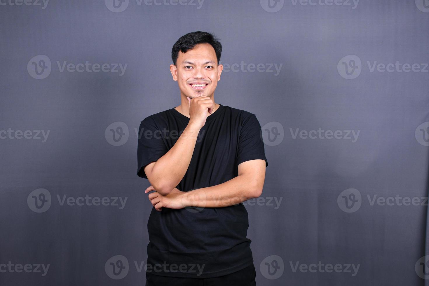 jeune homme asiatique pensant à des choses ou à une idée portant un t-shirt noir. fond gris isolé photo