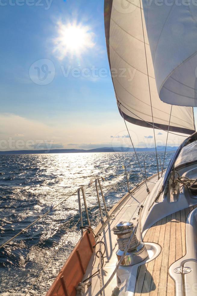 Yacht naviguant vers le coucher du soleil sur la mer bleue photo