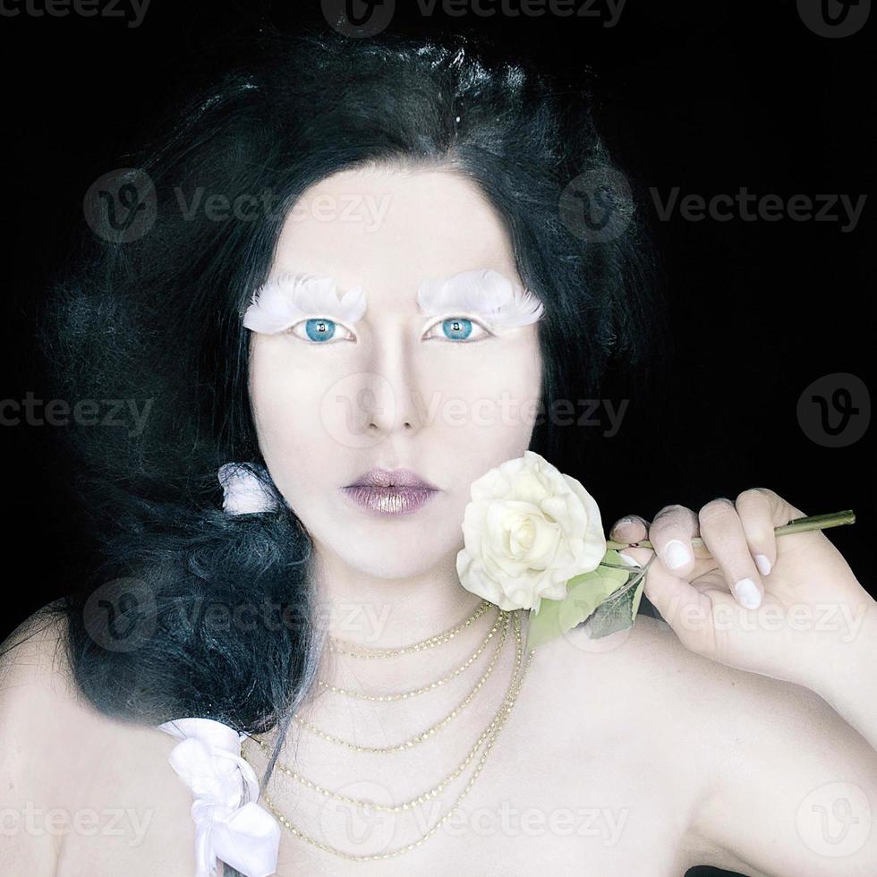 portrait conceptuel d'une femme étrange dans une couronne de roses blanches avec un maquillage fantastique photo