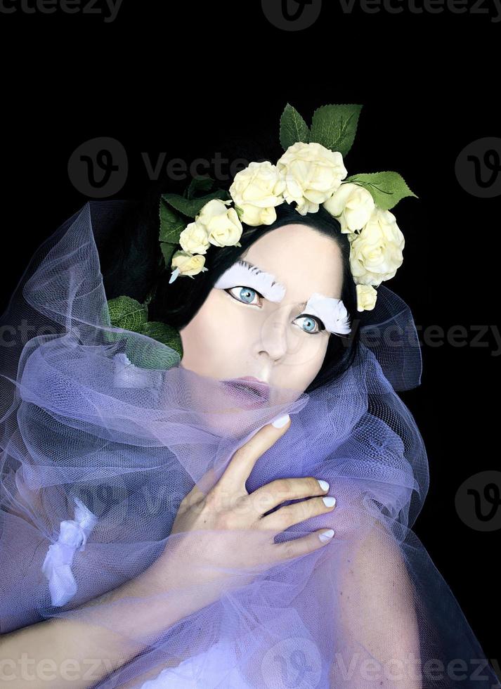 portrait conceptuel d'une femme étrange dans une couronne de roses blanches avec un maquillage fantastique pour da de muertos photo