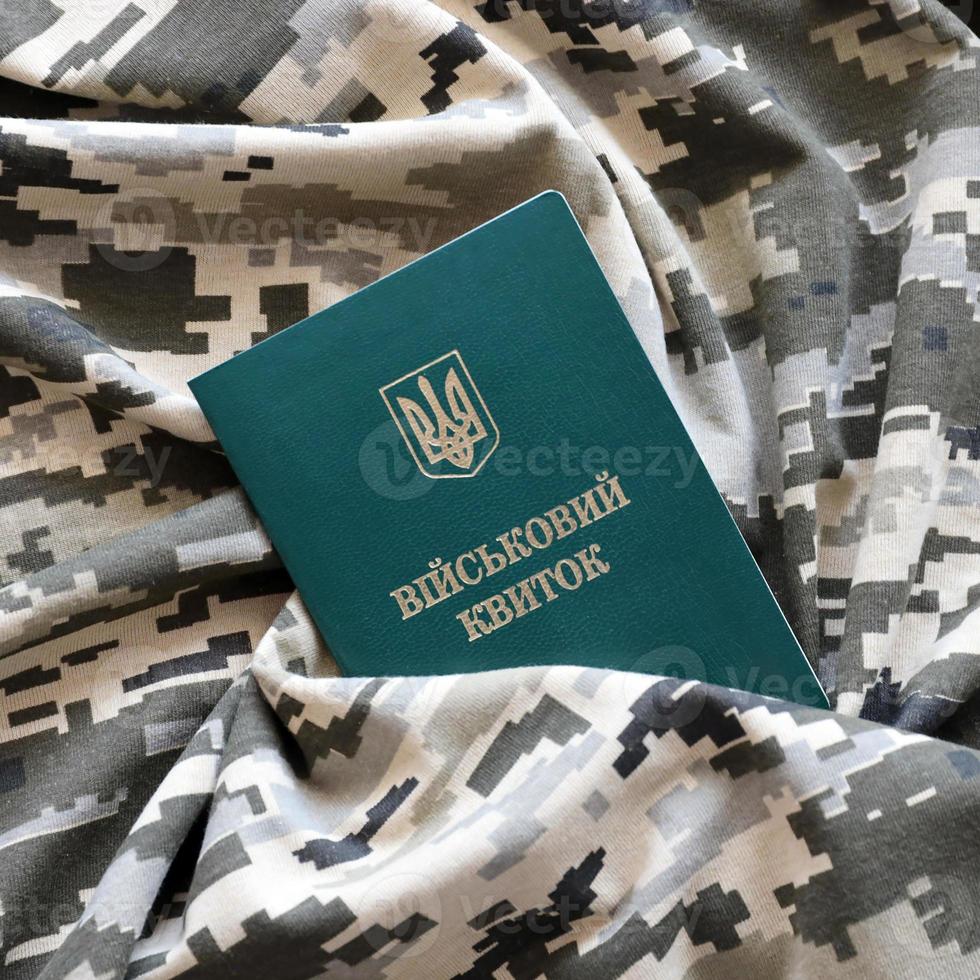 carte d'identité militaire ukrainienne sur tissu avec texture de camouflage pixélisé. tissu avec motif camouflage en formes de pixels gris, marron et vert avec jeton personnel de l'armée ukrainienne photo