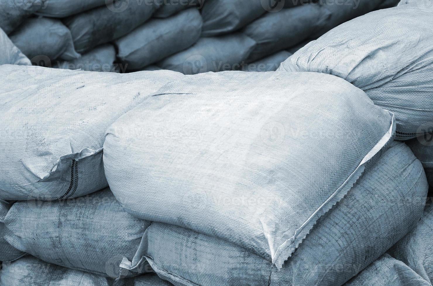 arrière-plan de nombreux sacs de sable sales pour la défense contre les inondations. barricade de protection en sacs de sable à usage militaire. beau bunker tactique photo