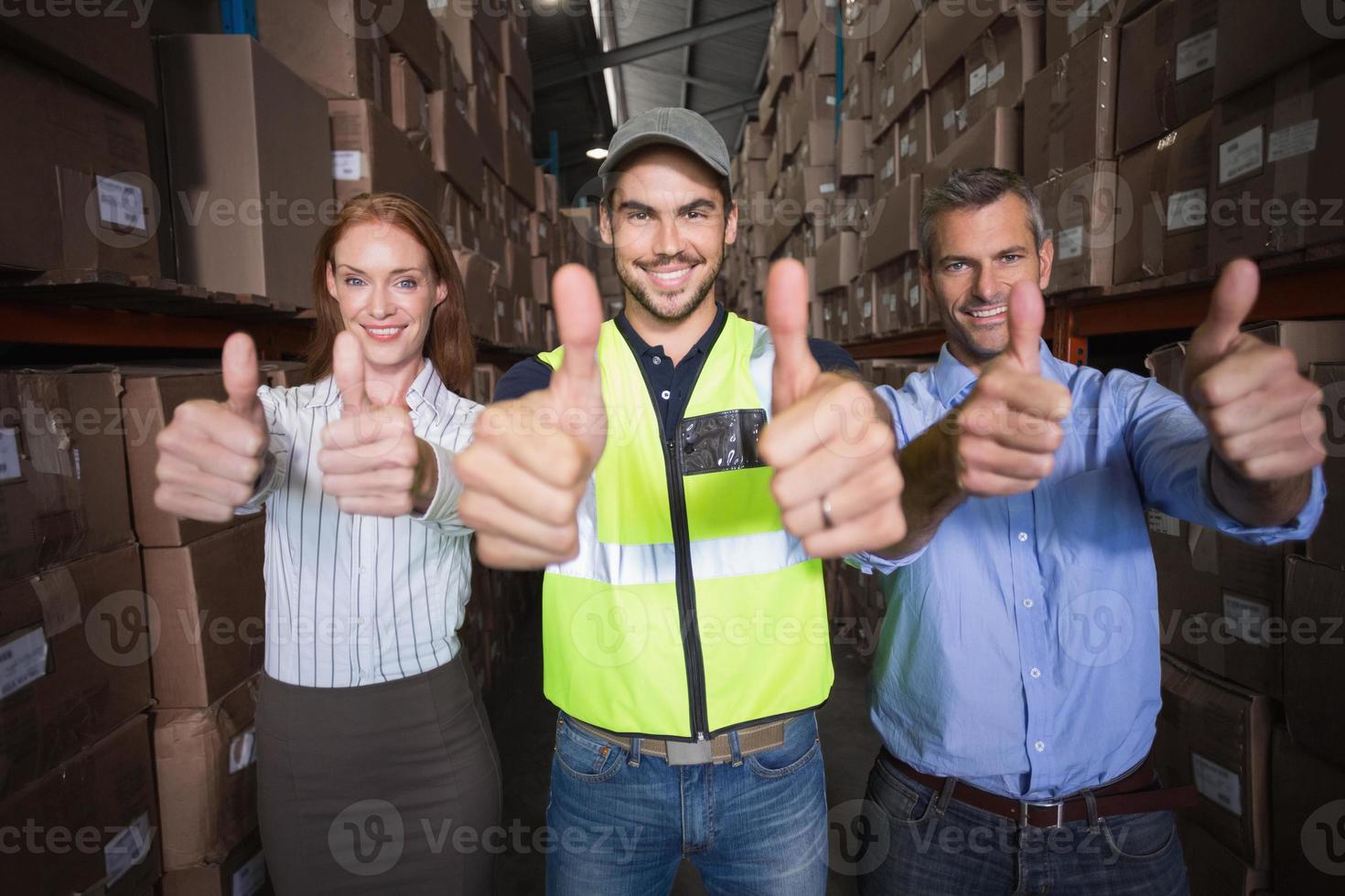 équipe d'entrepôt souriant à la caméra montrant les pouces vers le haut photo