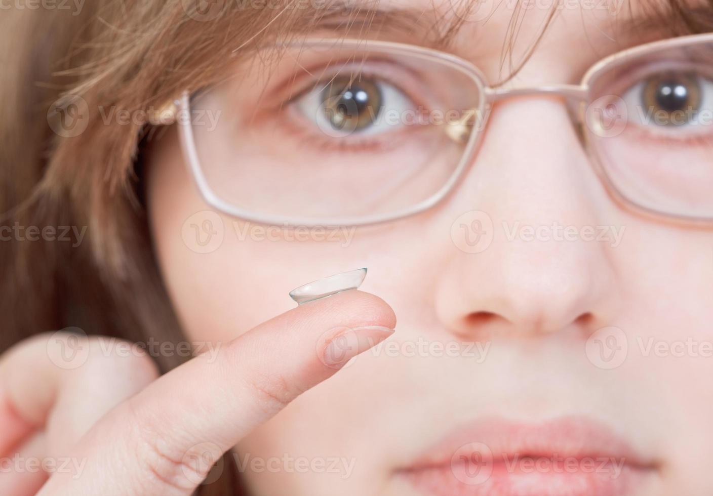 fille avec des lunettes tient une lentille de contact photo