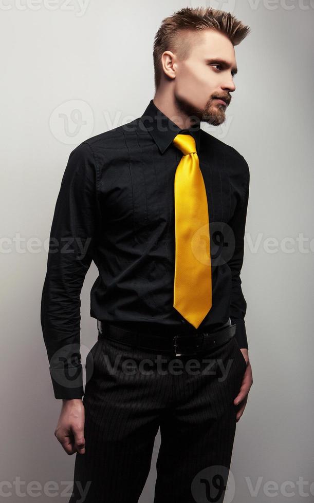 élégant jeune bel homme en chemise noire et cravate jaune. photo