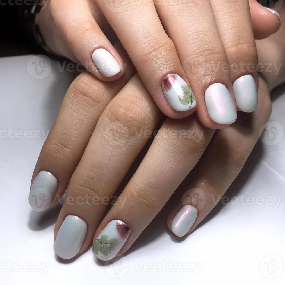 manucure blanche féminine sur les ongles sur un fond sombre photo